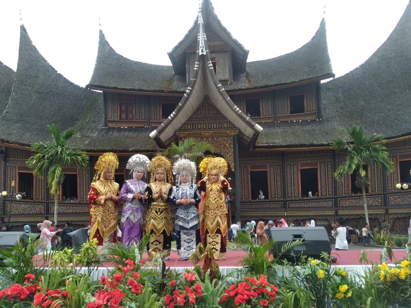 Pelawat dalam busana tradisi Minangkabau di hadapan rumah gadang.